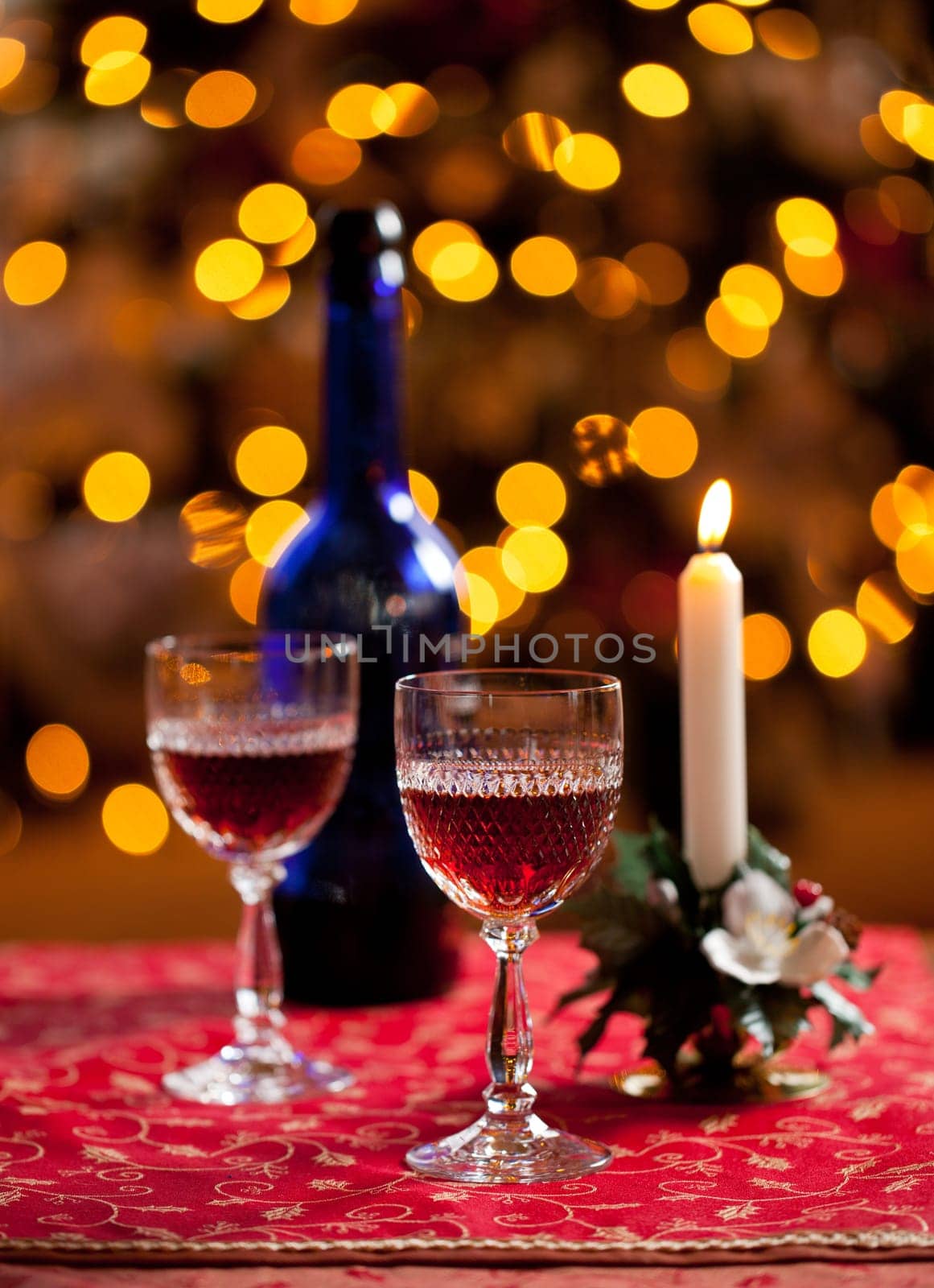 Cut glass sherry or port glasses in front of an out of focus christmas tree with blue bottle