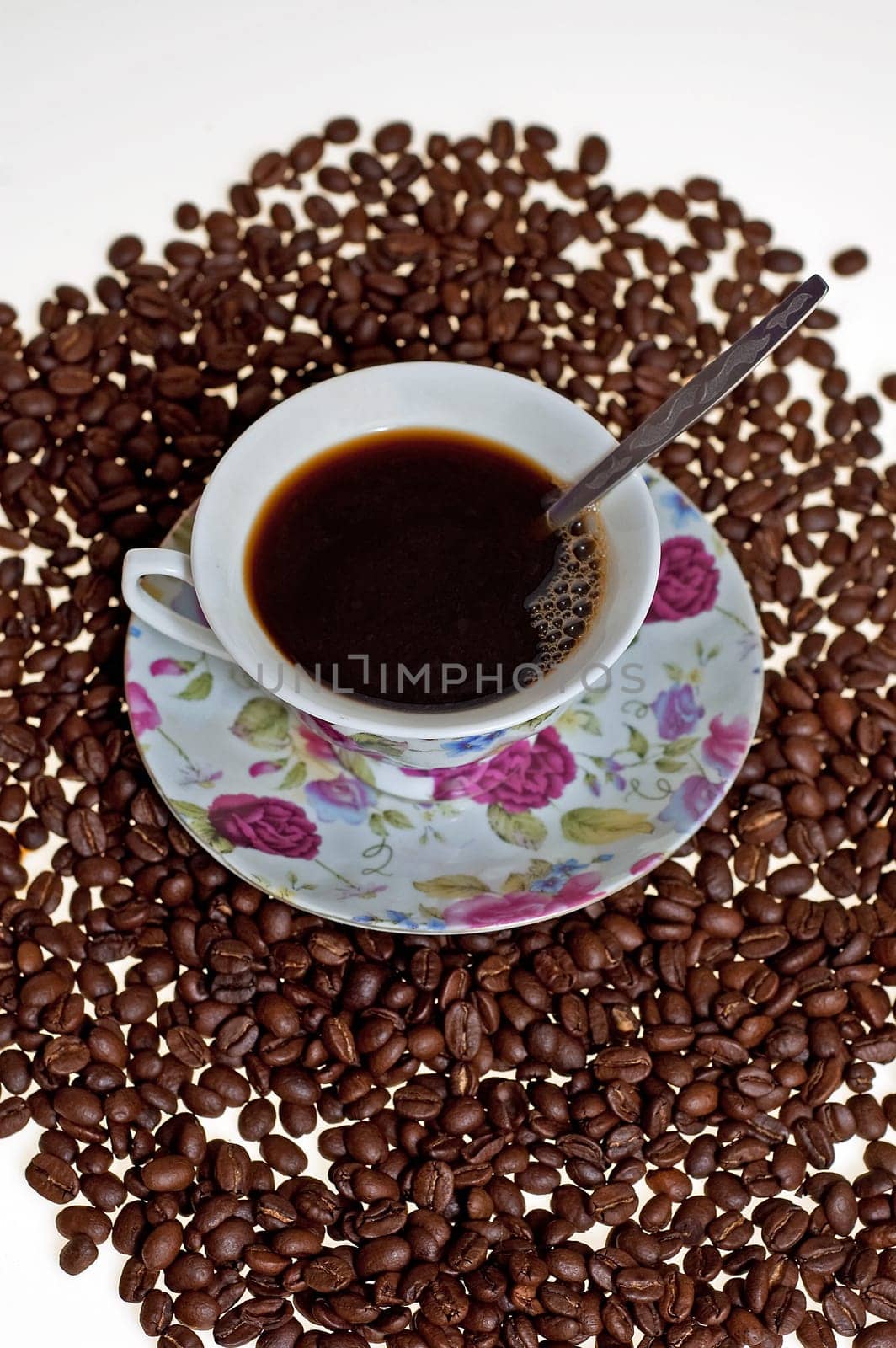 A cup in a pile of coffe beans on white background.