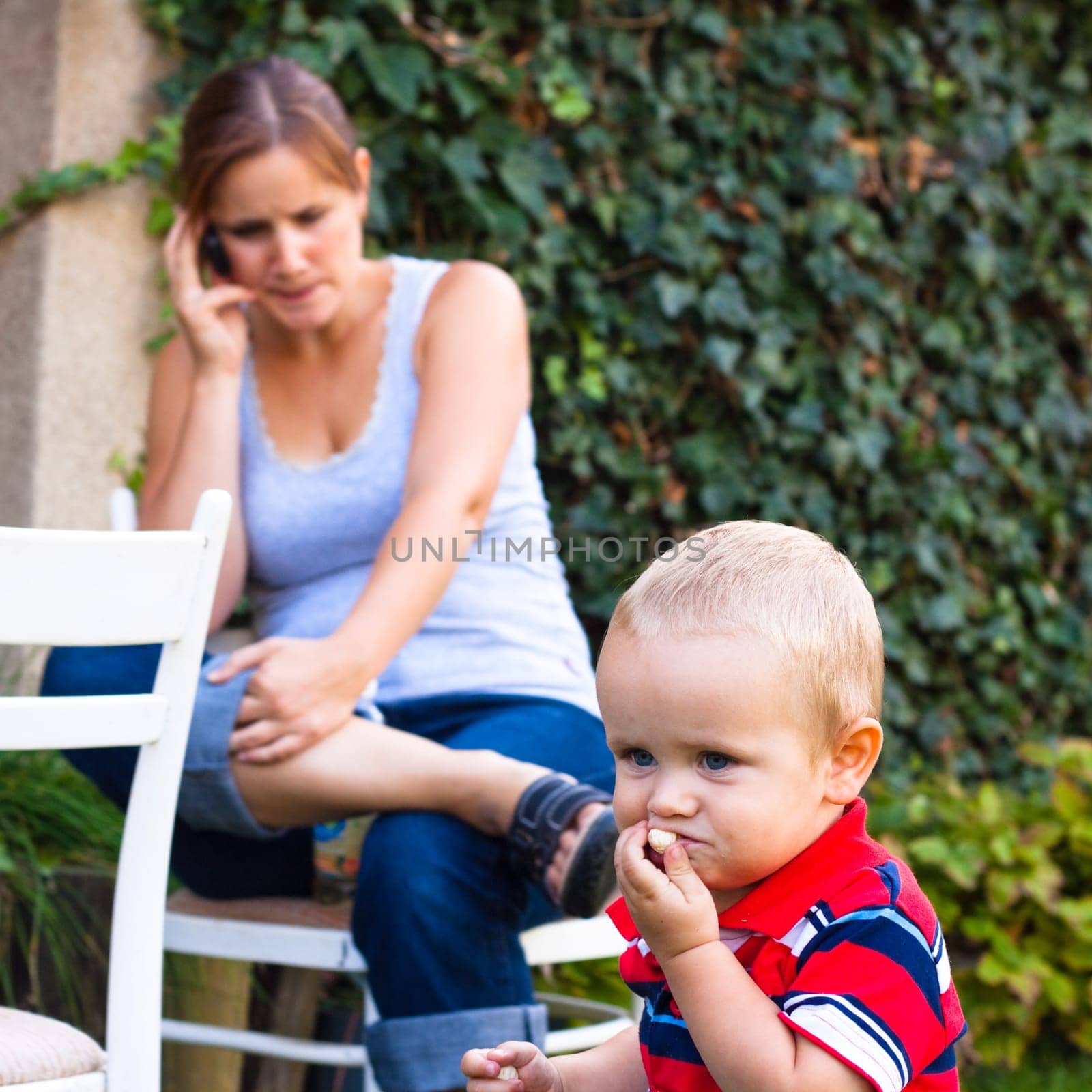 Young woman on the phone and a little boy outdoors.