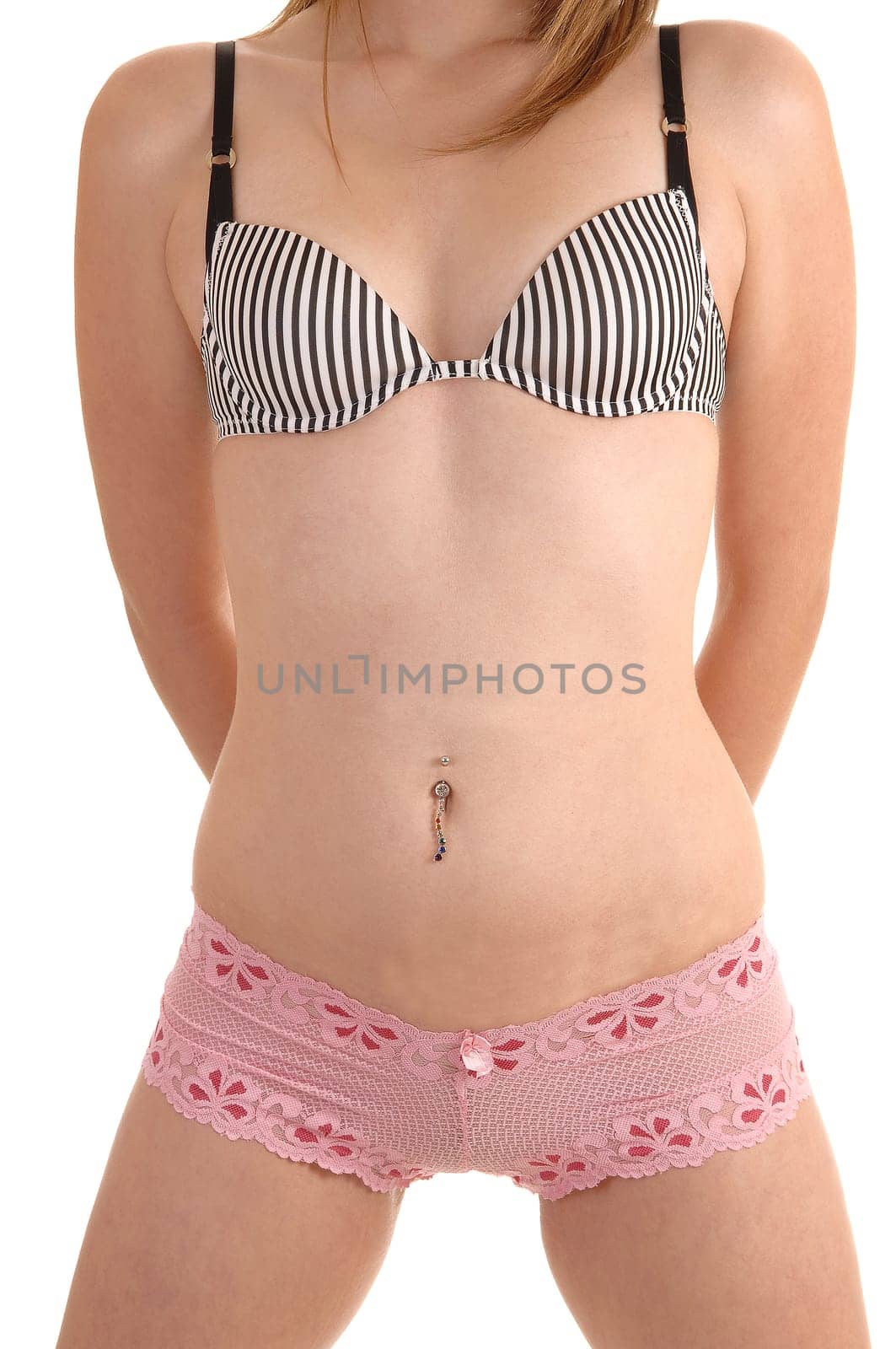 The midsection of a young slim woman in pink panties and a bra with jewelery in her bellybutton and a nice flat stomach, over white background.