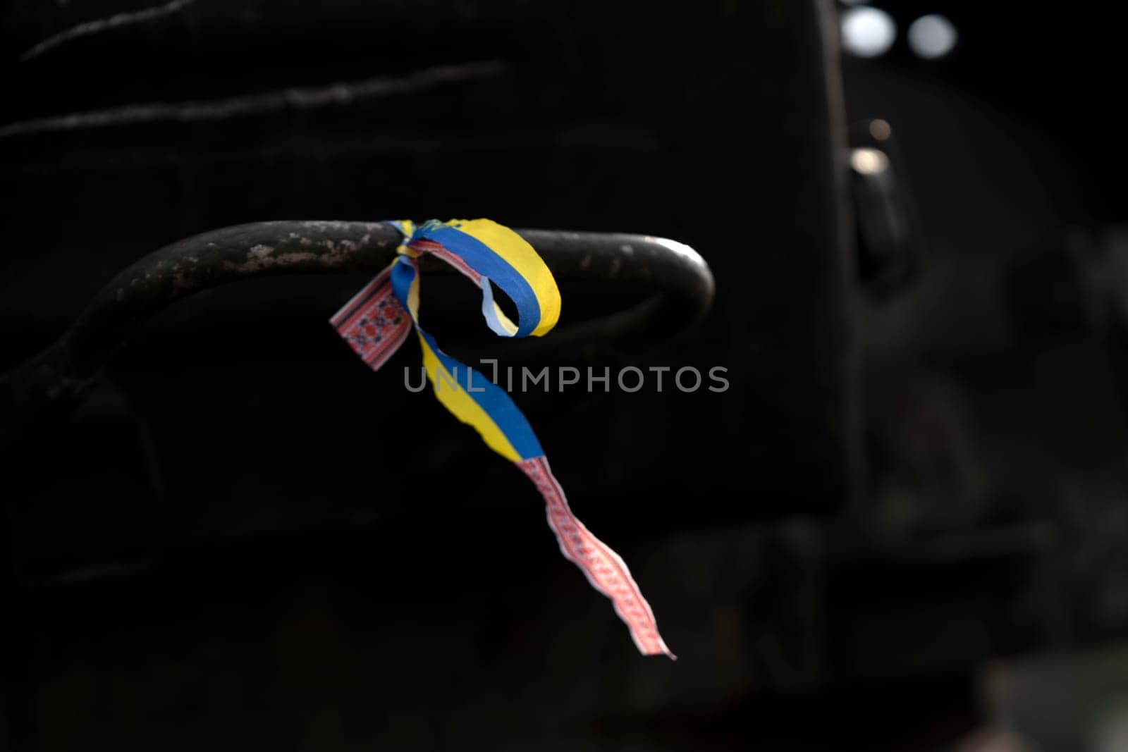 A ribbon with a Ukrainian blue and yellow flag attached to military equipment, a concept on the theme of the war and events in Ukraine, close-up view.