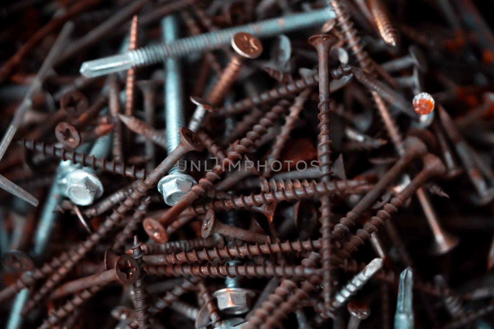 Screws and nails, tools for repair work, connection of structures, construction and handicraft closeup view on the dark background.