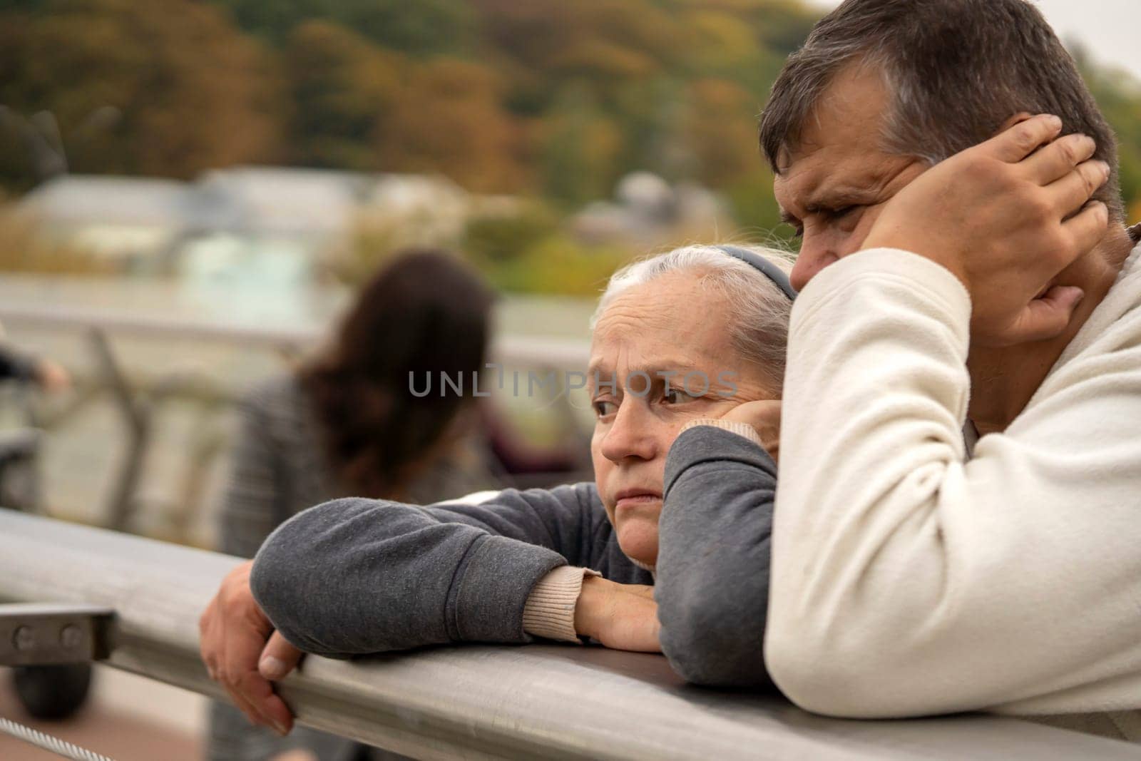 An elderly couple with sad faces outdoors, a man and a woman in an old age are experiencing a crisis in a relationship or depression, support each other in a difficult life moment.