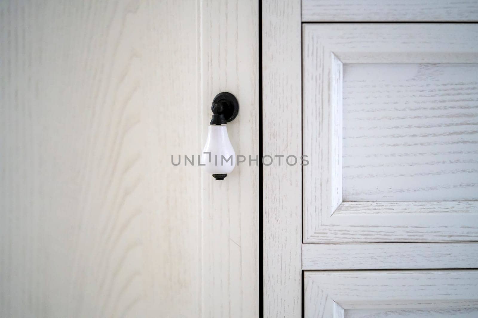 Doors and fittings of a vintage wooden cabinet or wardrobe closeup view, white-painted wood in a modern classic style.