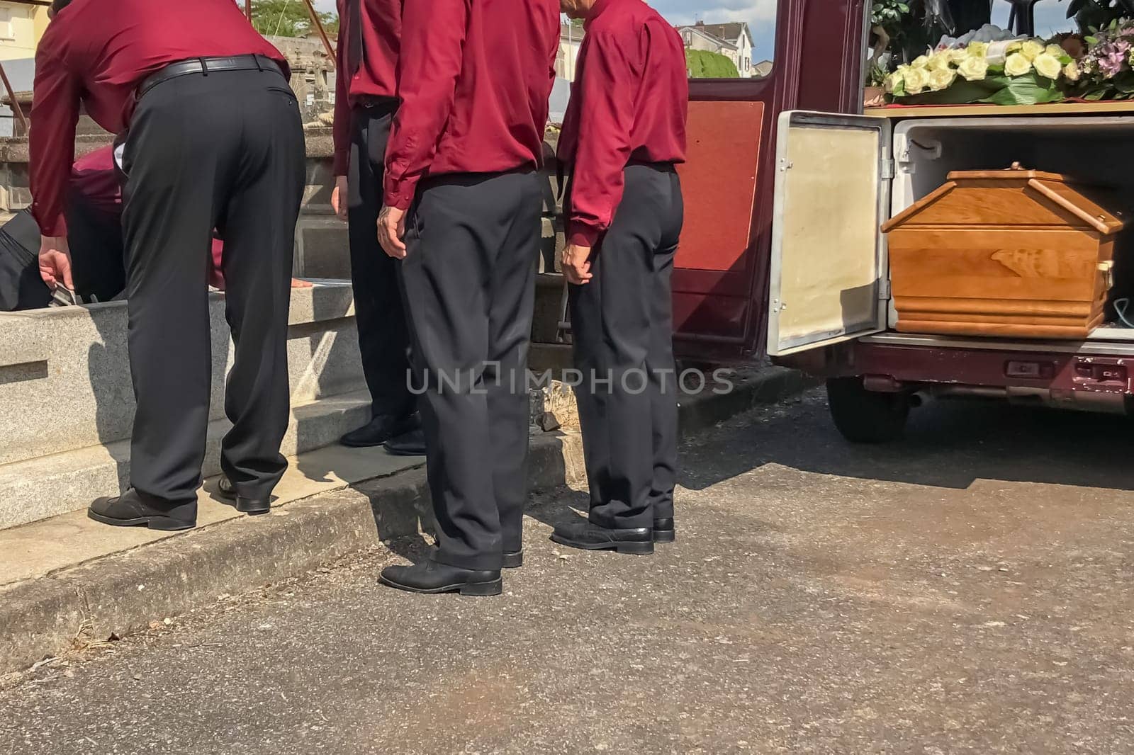 Porters lower the coffin into the grave in the cemetery