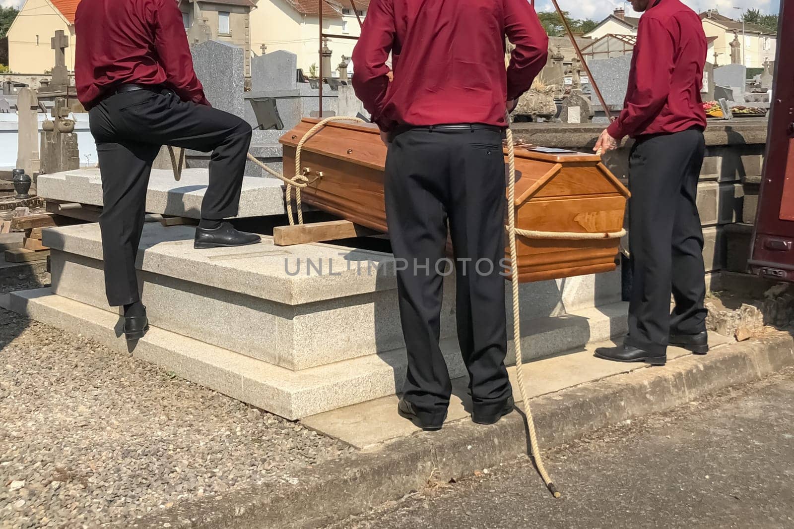 Porters lower the coffin into the grave in the cemetery