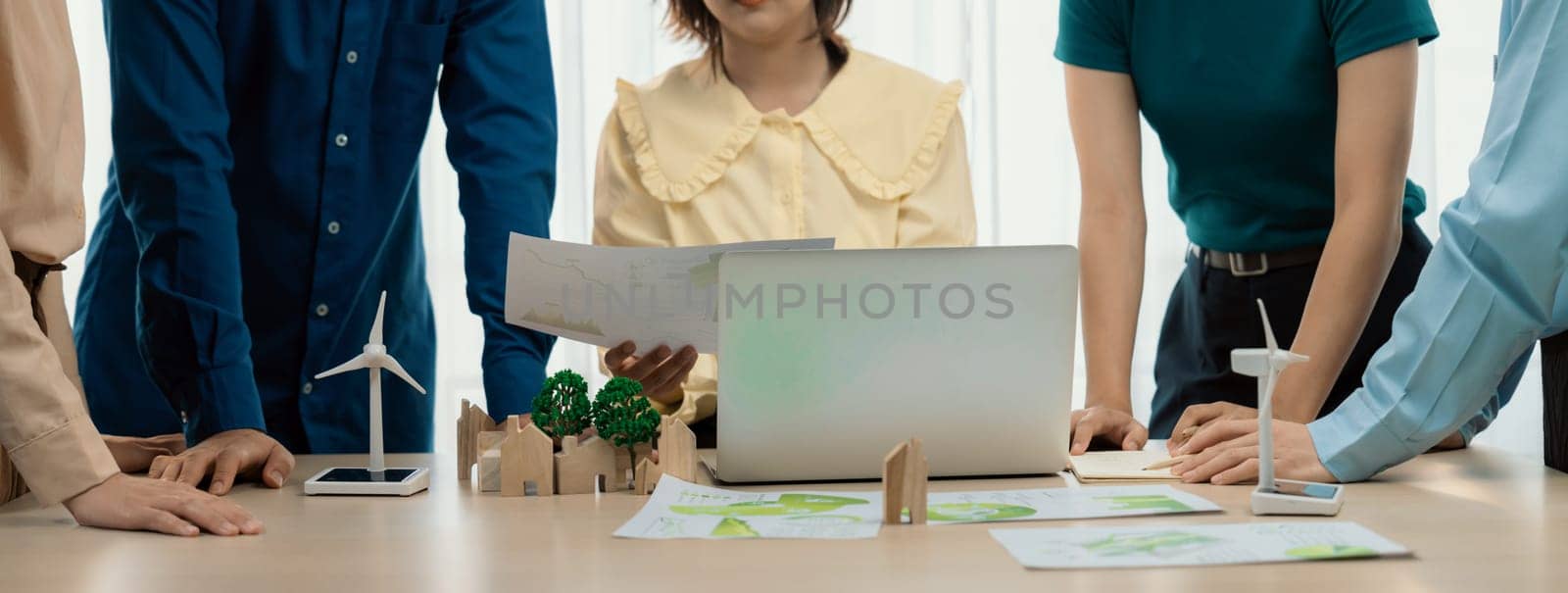 Professional business team prepare to present green business on table with windmill presented using renewable energy, wooden block and environmental document scatter around. Closeup. Delineation.