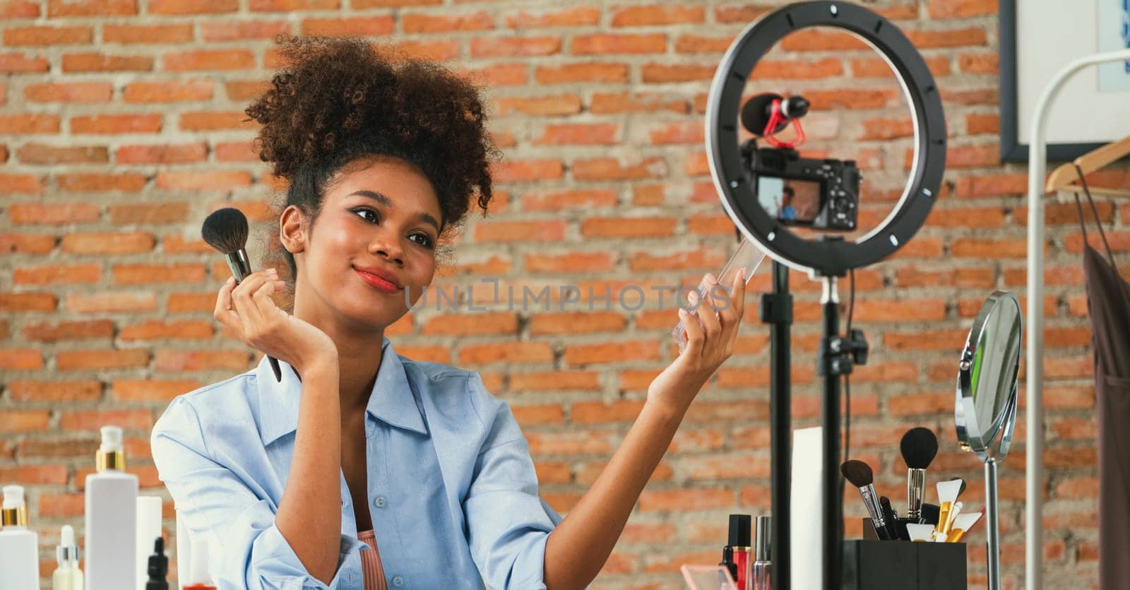 Woman influencer shoot live streaming vlog video review makeup crucial social media or blog. Happy young girl with cosmetics studio lighting for marketing recording session broadcasting online.