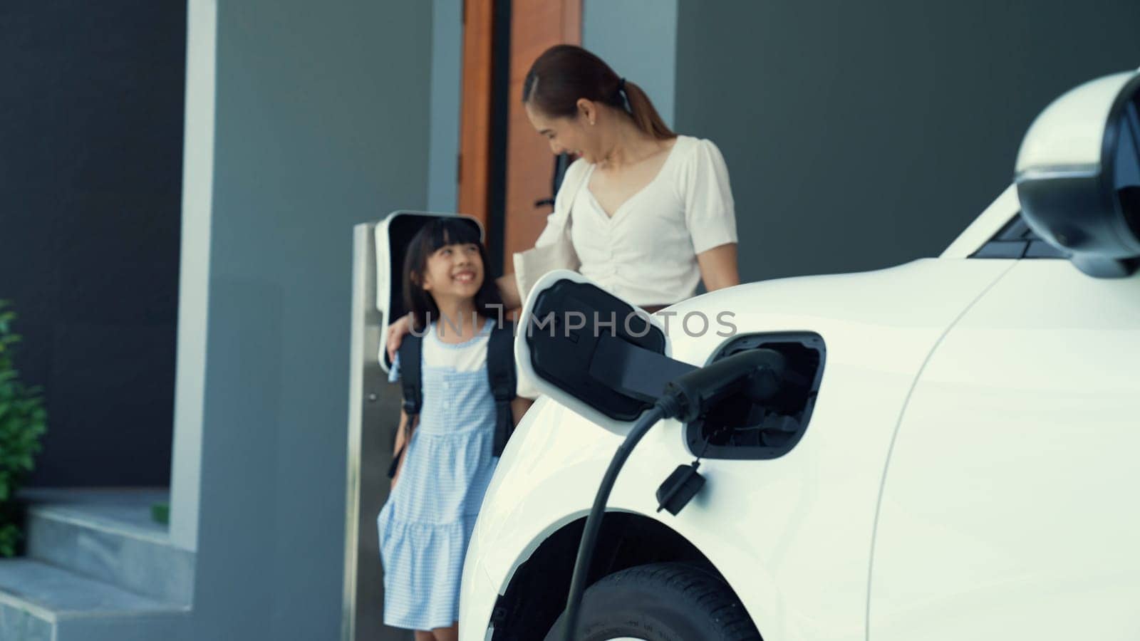 Progressive lifestyle of mother and daughter with EV car and charging station. by biancoblue