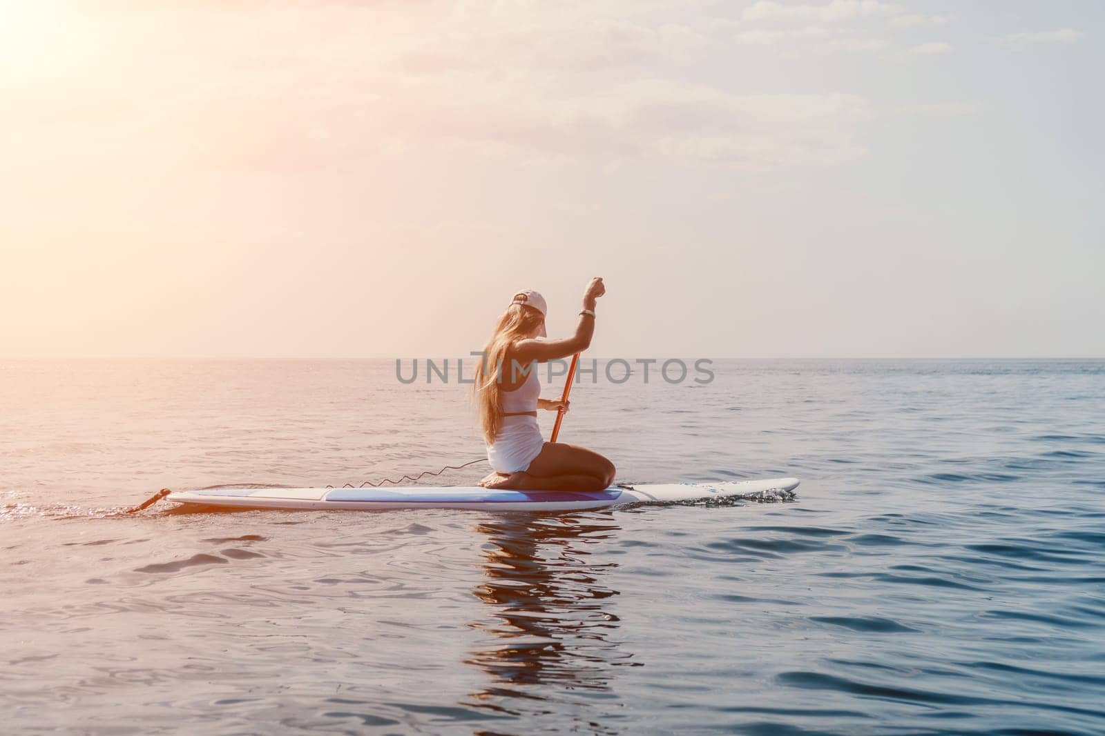 Woman sea sup. Close up portrait of happy young caucasian woman with long hair looking at camera and smiling. Cute woman portrait in bikini posing on sup board in the sea by panophotograph