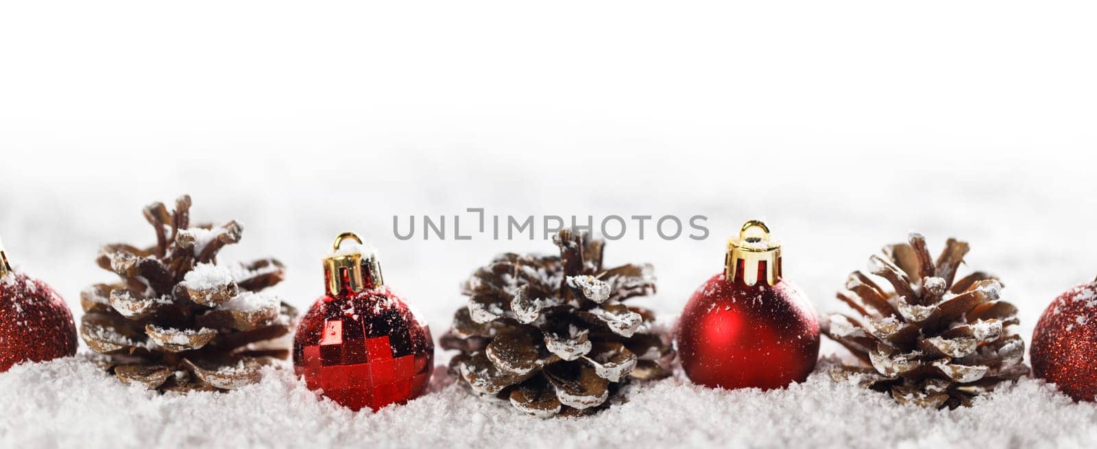 Red christmas balls and pine cones isolated on snow, Christmas banner