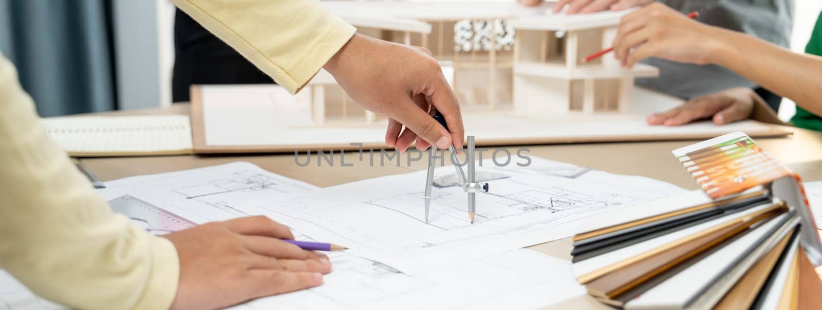 Professional architect team select sustainable house materials while skilled engineer using divider measure blueprint with house model and color palette placed on meeting table. Closeup. Variegated.