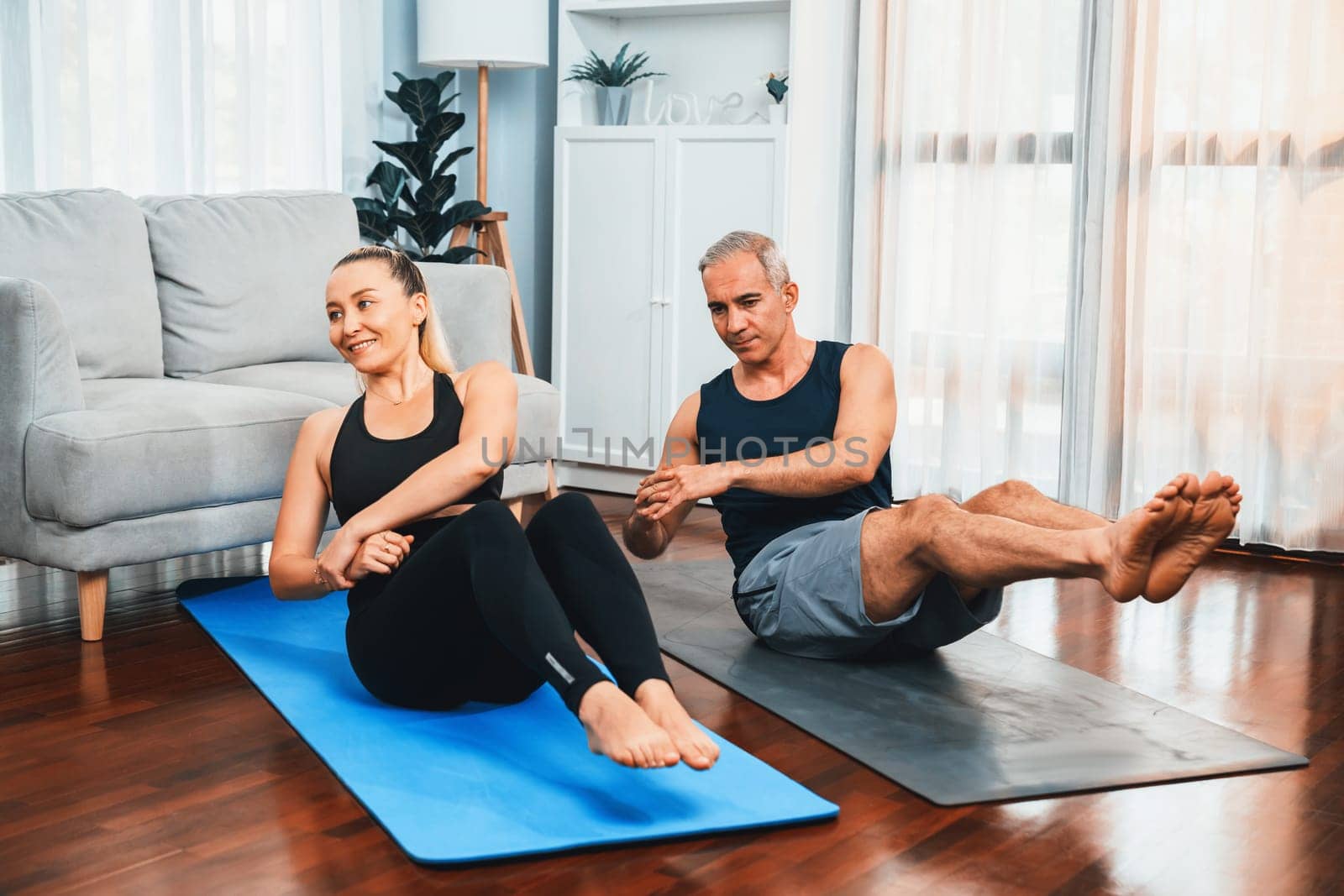 Athletic and sporty senior couple engaging matt exercising and doing crunch together at home exercise as concept of healthy fit body lifestyle after retirement. Clout