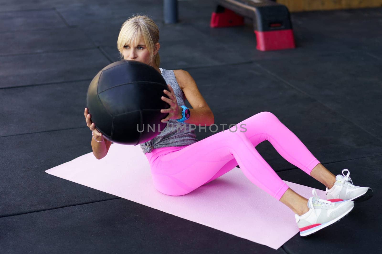 Sportswoman doing exercises with medicine ball on mat in gym by javiindy