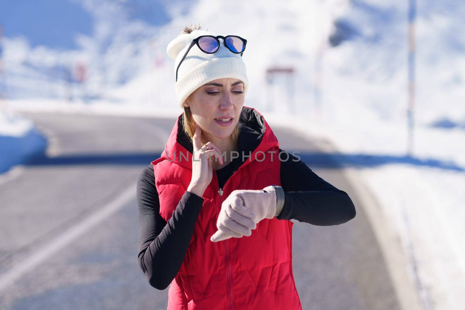 Sportive woman checking pulse on winter road by javiindy