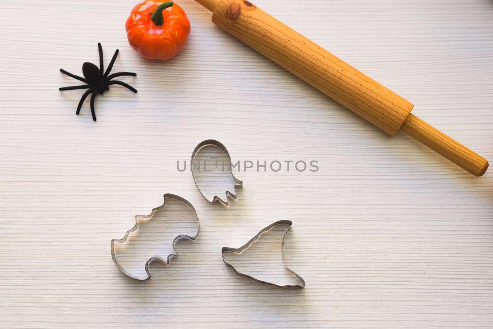 Making cookies for Halloween. A woman cuts out cookies from the dough in the form of pumpkin, cat, Ghost and bat.