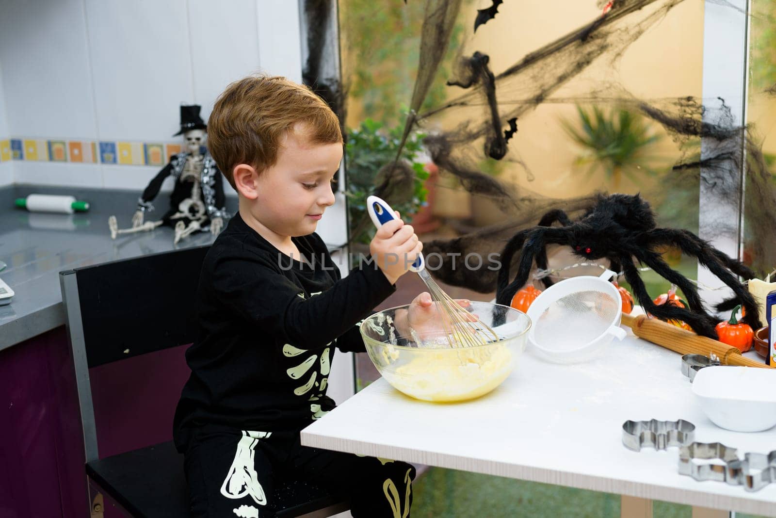 boy dressed as a skeleton preparing halloween cookies.Happy boy preparing for halloween. Festival in the kitchen..