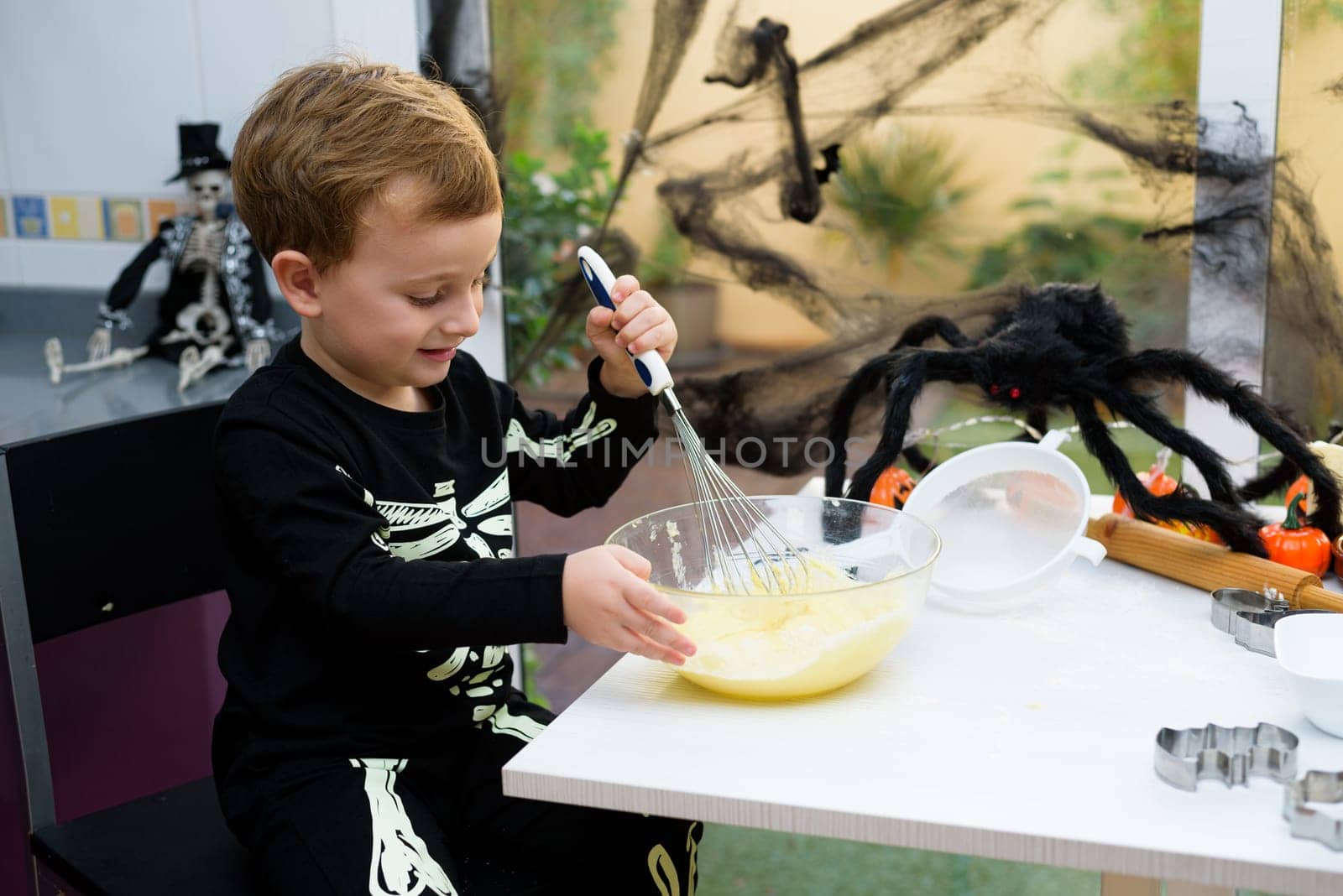 boy dressed as a skeleton preparing halloween cookies.Happy boy preparing for halloween. Festival in the kitchen