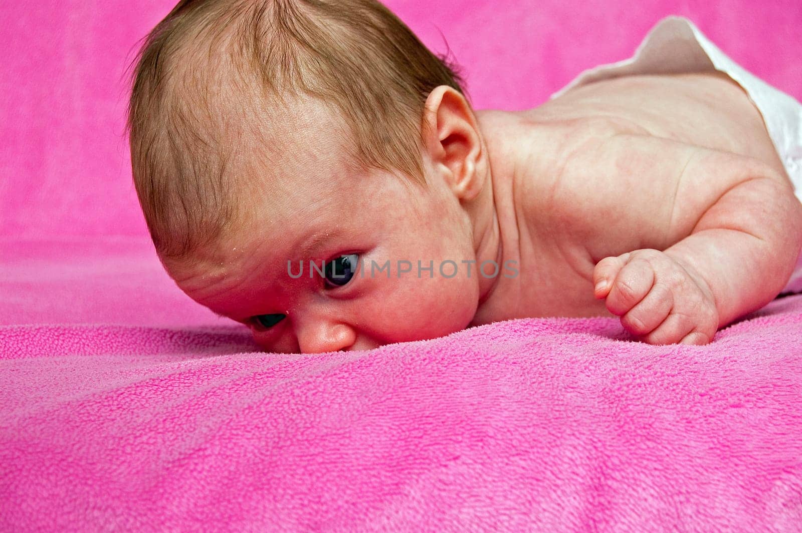 Baby lying on her tummy and a pink blanket