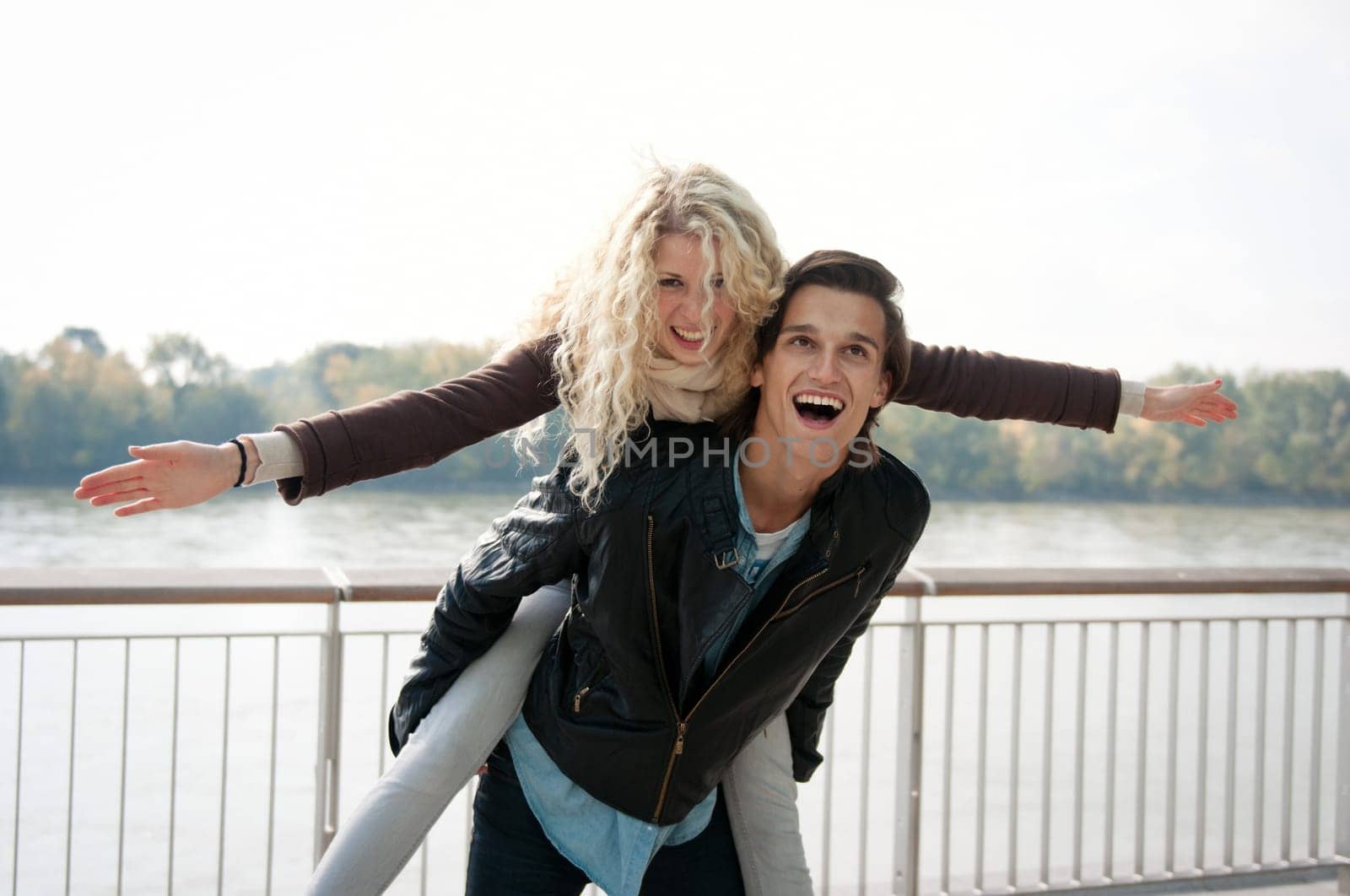 Young couple enjoying life together outdoor - man holding woman who pretends to fly