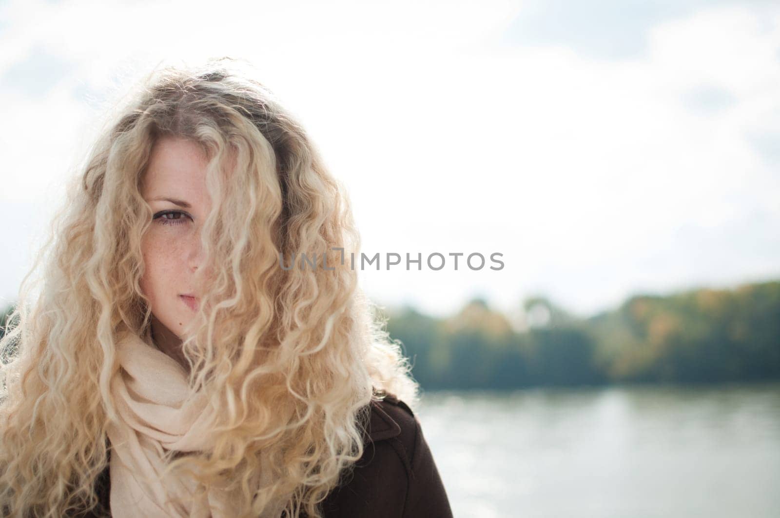 Portrait of young woman with blond hair covering one eye outdoor with copy space