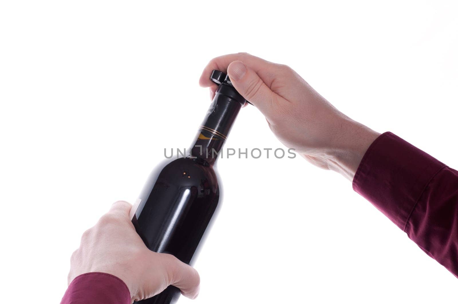 Two hands remove the capsule of a wine bottle with a capsule knife