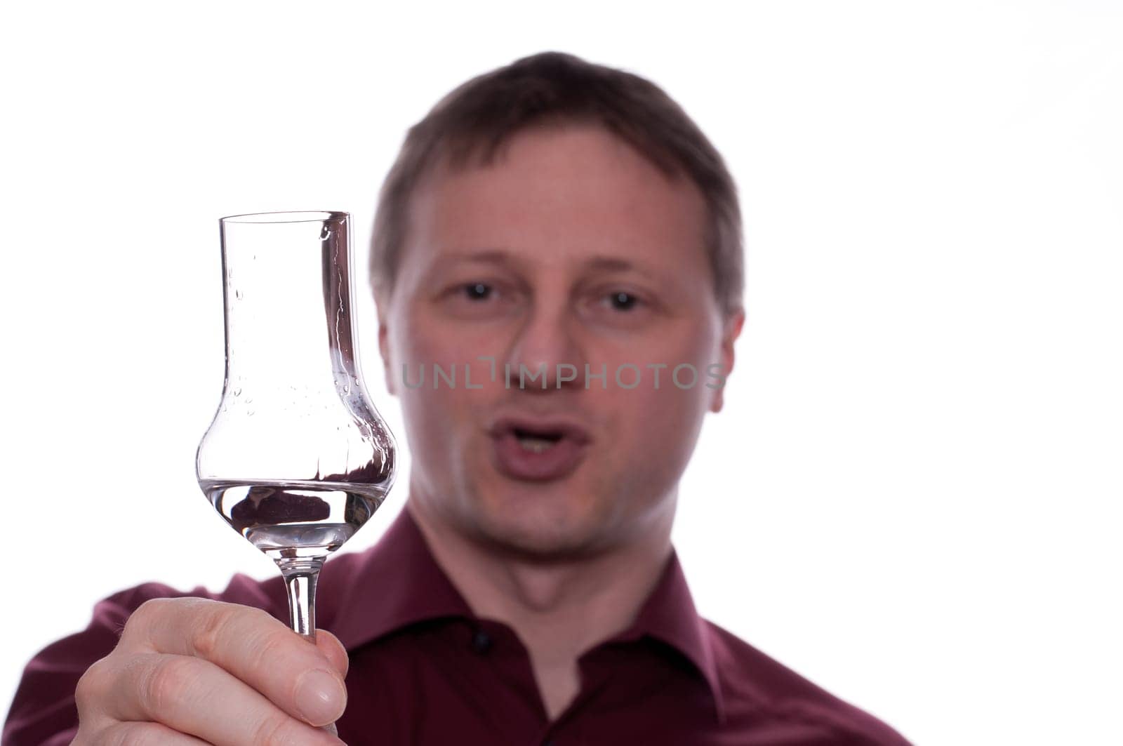 A man holds a glass of grappa forward