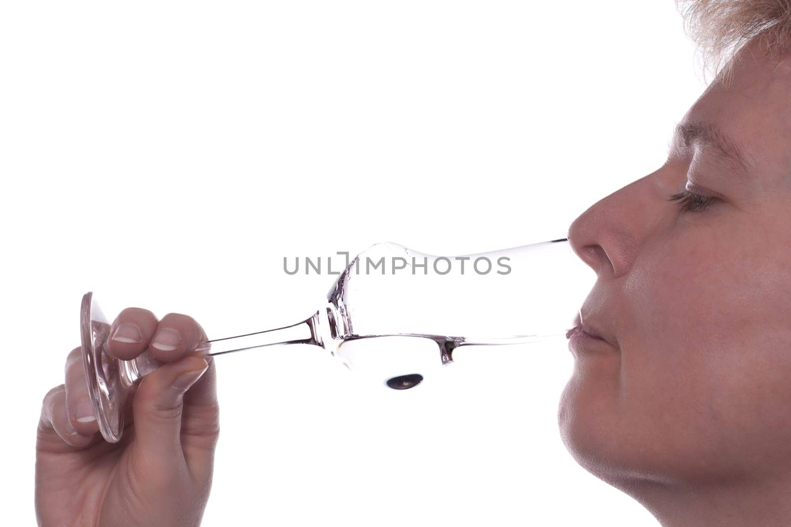 A blonde woman drinks a grappa from a glass