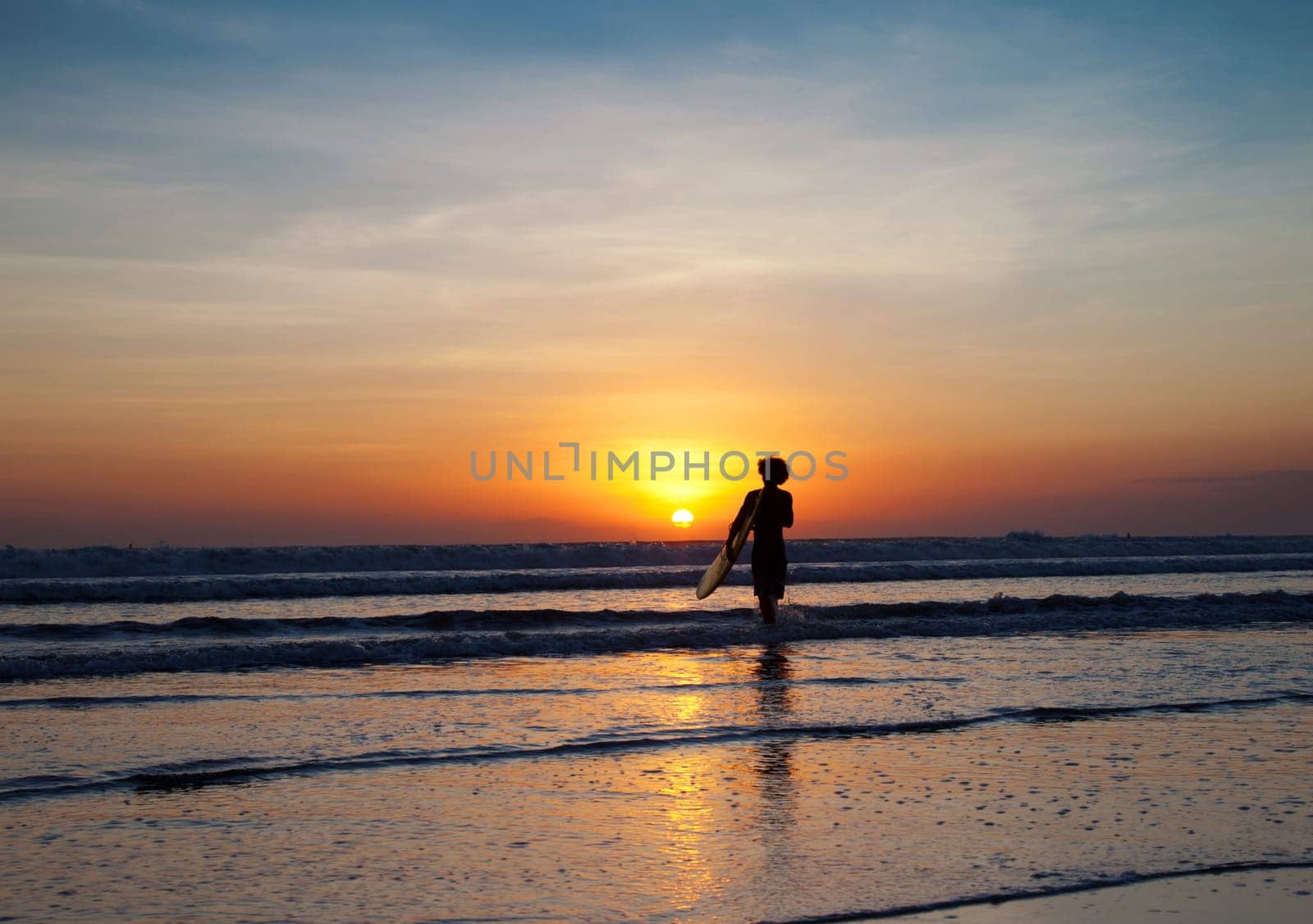 Surfer and waves at sunset in Bali, Indonesia