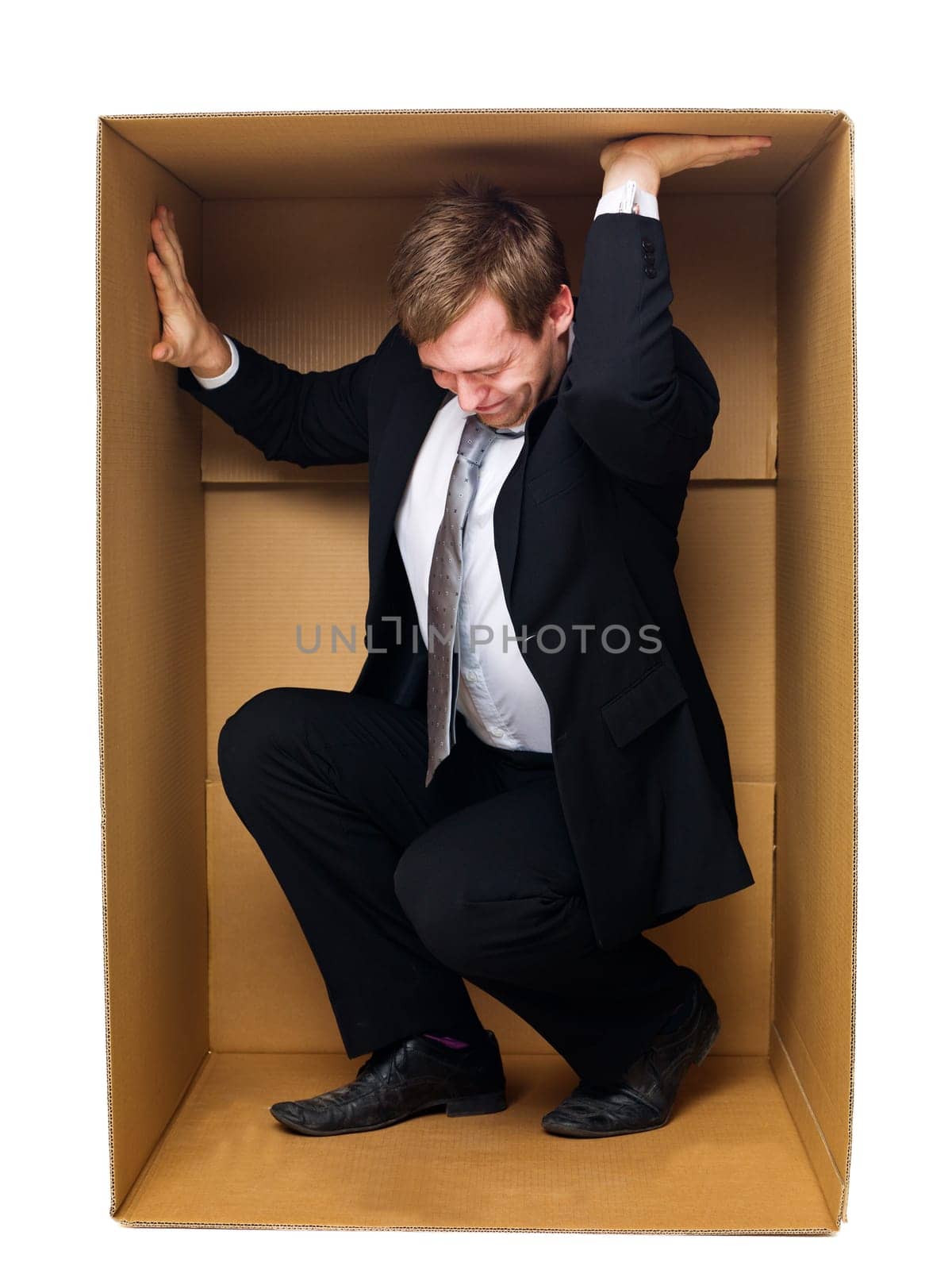 Well dressed businessman in a tight cardboard box isolated on white background