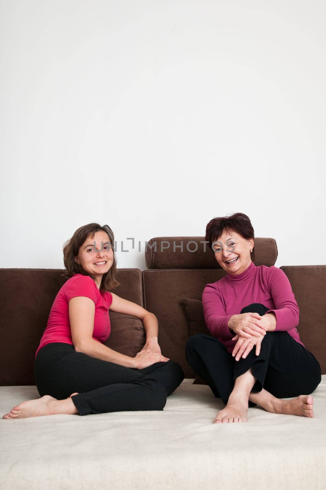 Portrait of happy senior mother and her daughter sitting on sofa at home