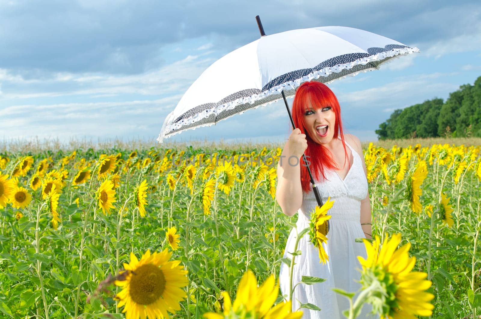 Young girl with an umbrella on a sunflower field