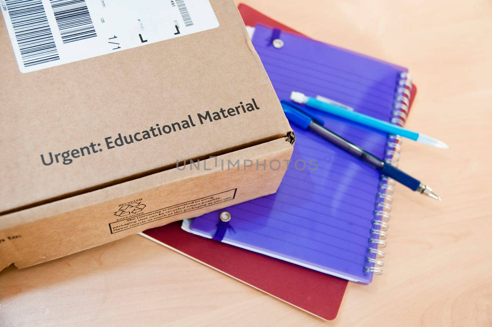High angle shot of distance learning cardboard box with notebooks underneath.