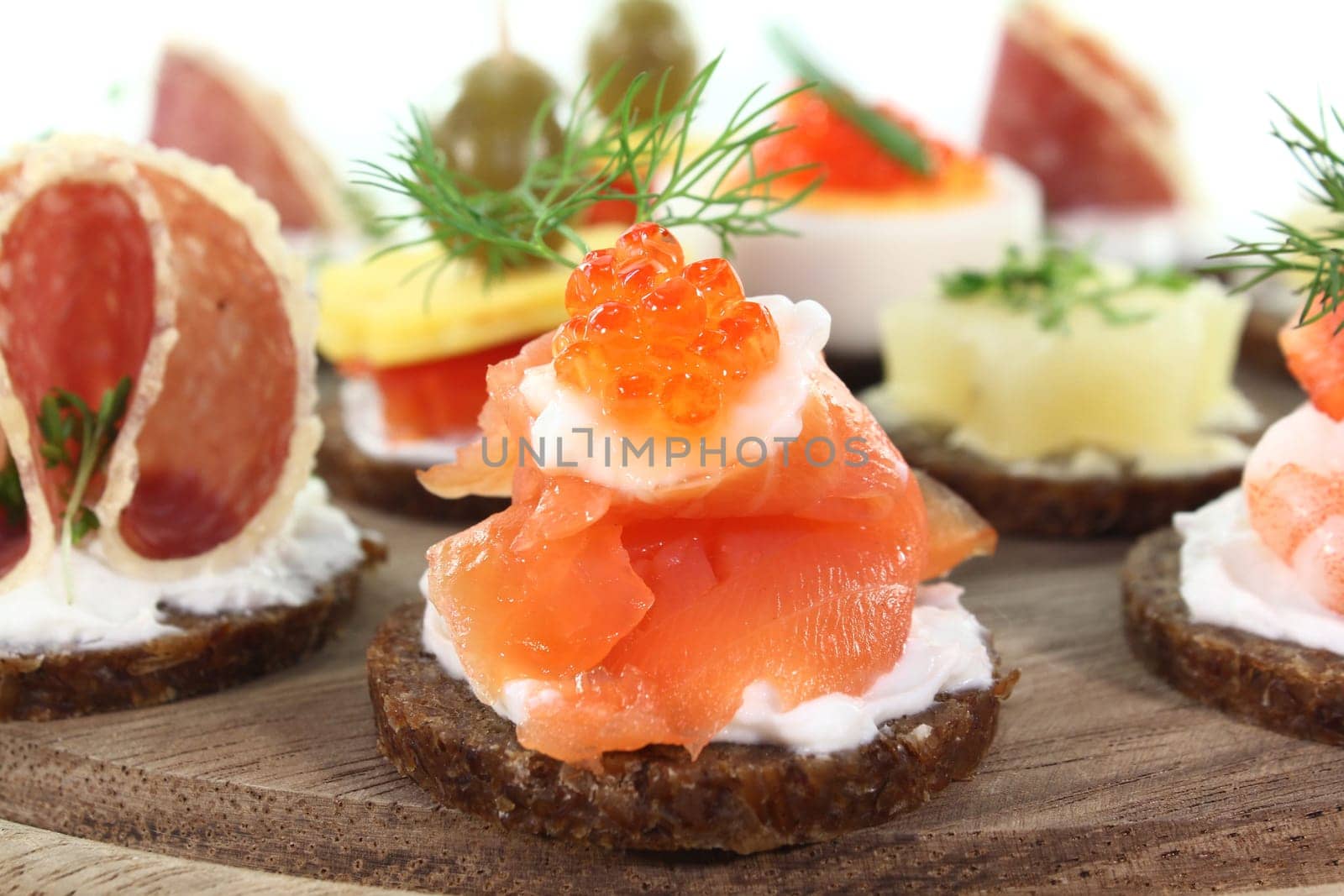 Various canapés on a wooden board against a white background
