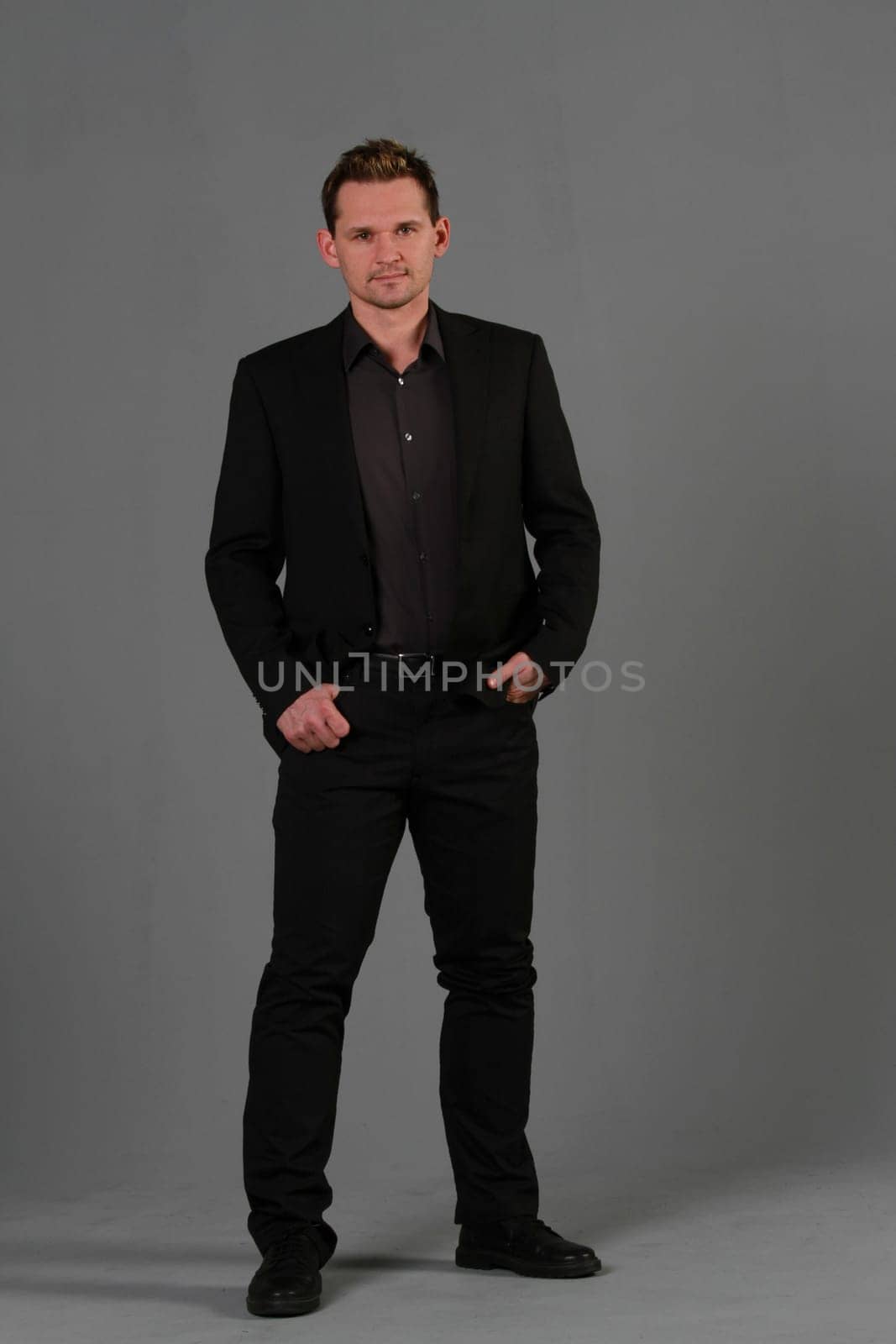 Business man in black suit on grey background in studio