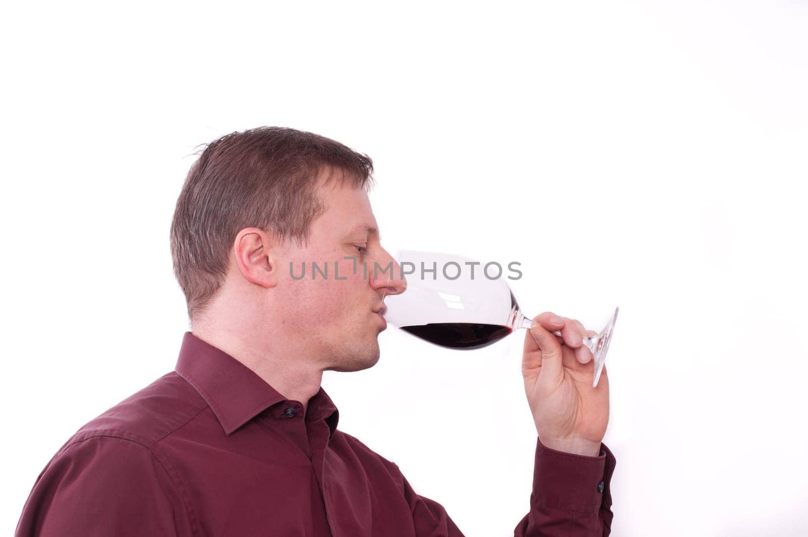 A man drinks a glass of red wine