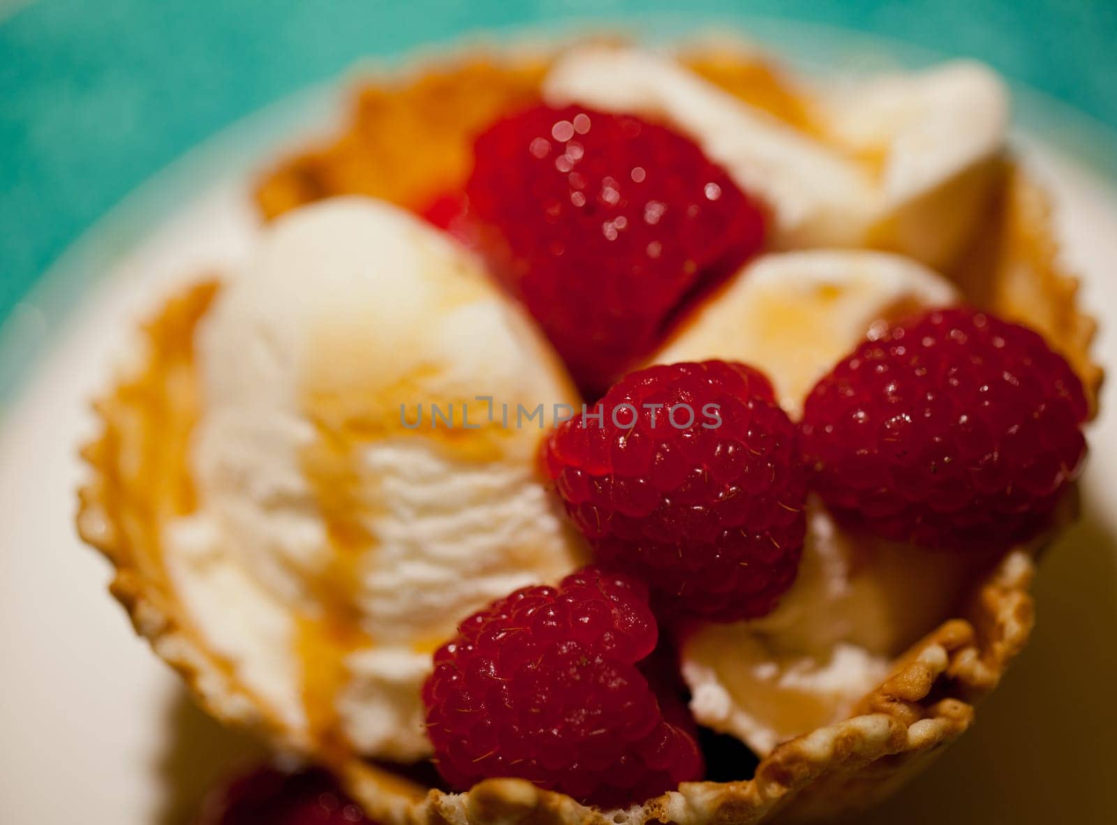 Raspberries and ice-cream with syrup in a biscuit bowl taken in macro close up