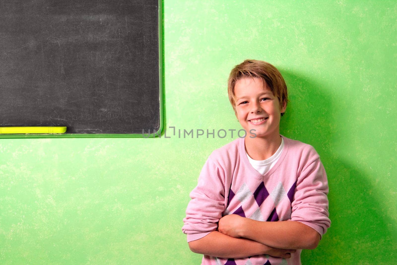 Young handsome student in colorful classroom next to blackboard
