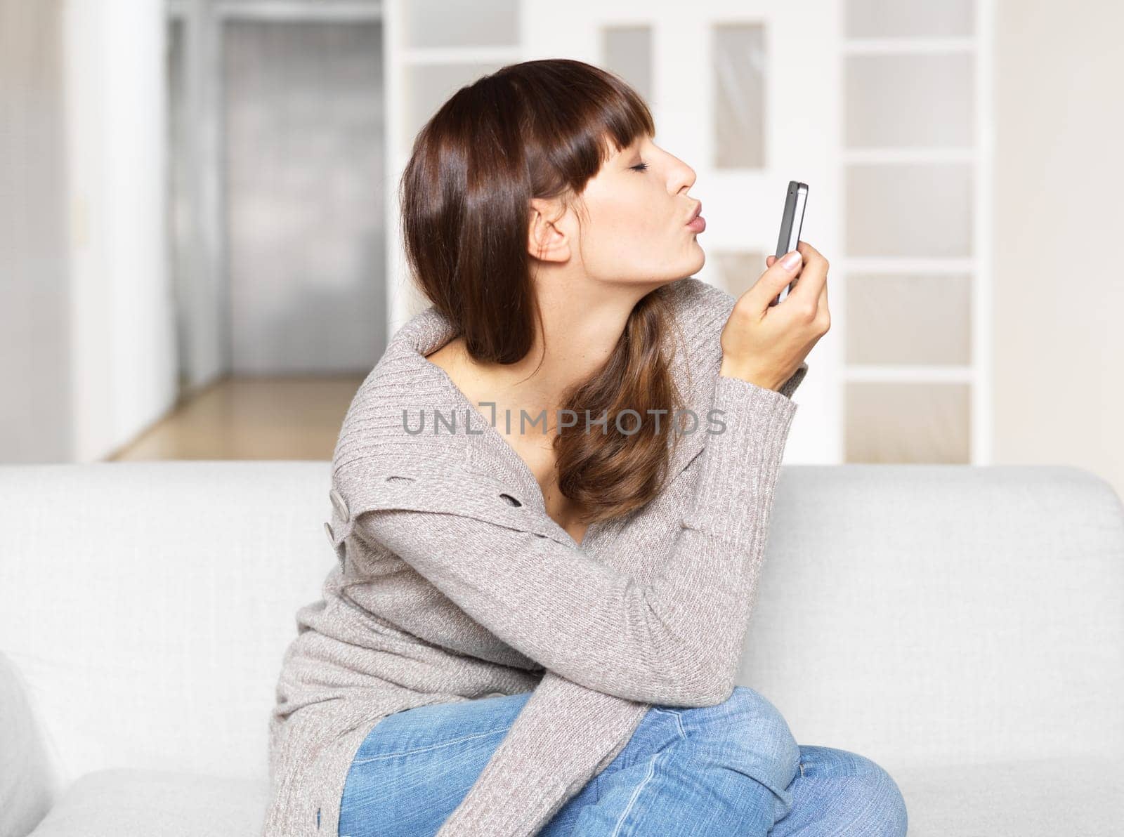 Young woman sends kisses via mobile phone / video chat
