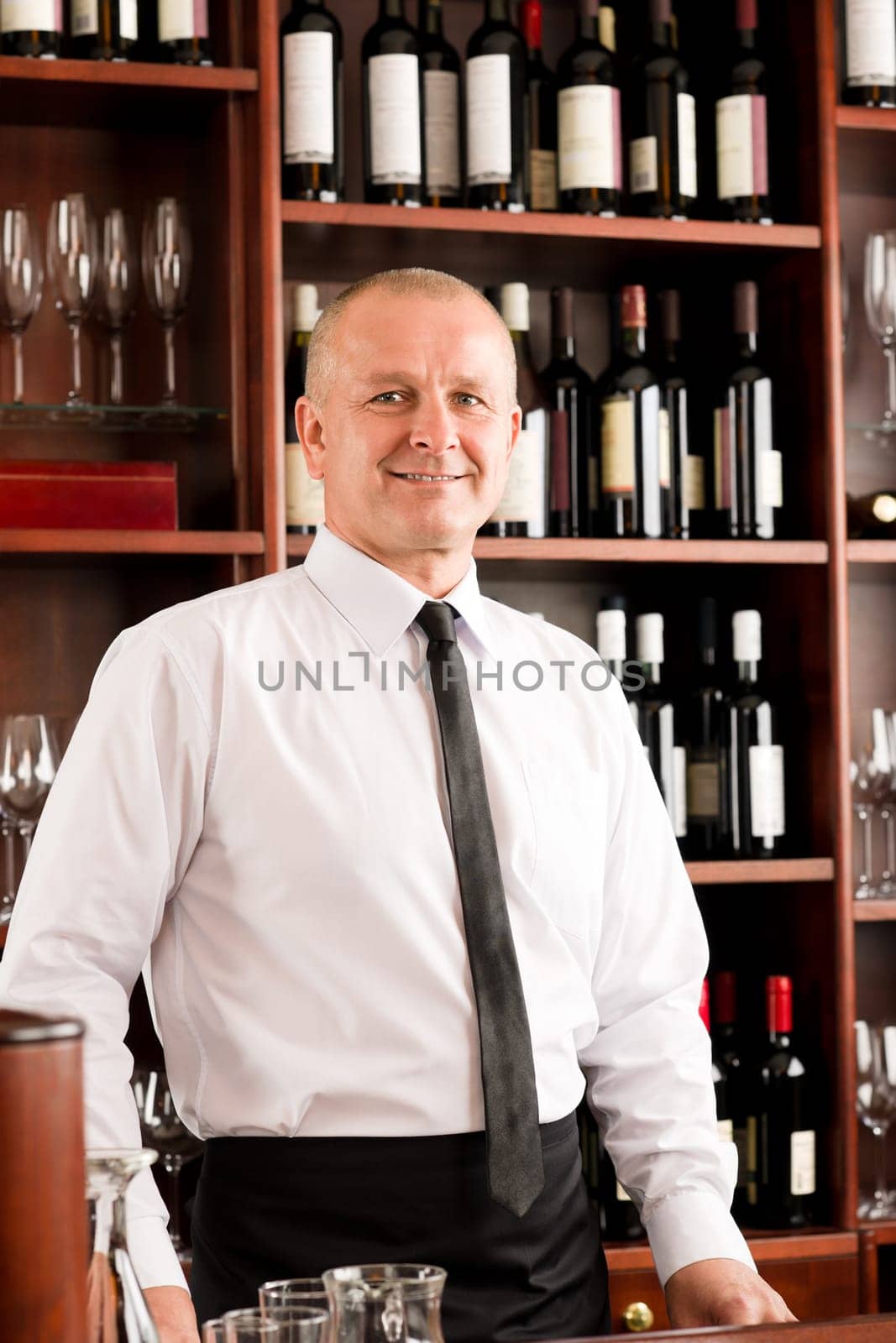 Wine bar waiter happy male in restaurant standing behind counter