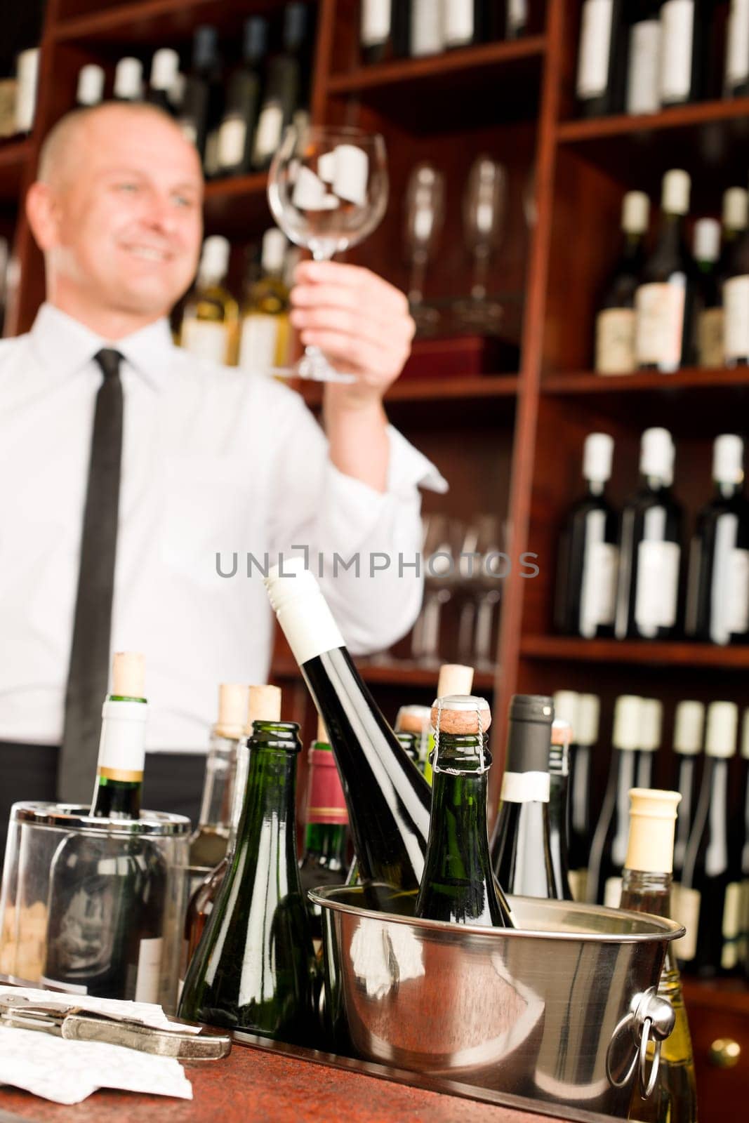 Wine bar waiter looking at clean glass in restaurant
