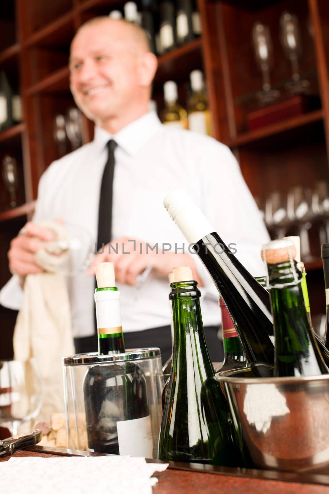 Wine bar bottles close-up waiter clean glass in restaurant