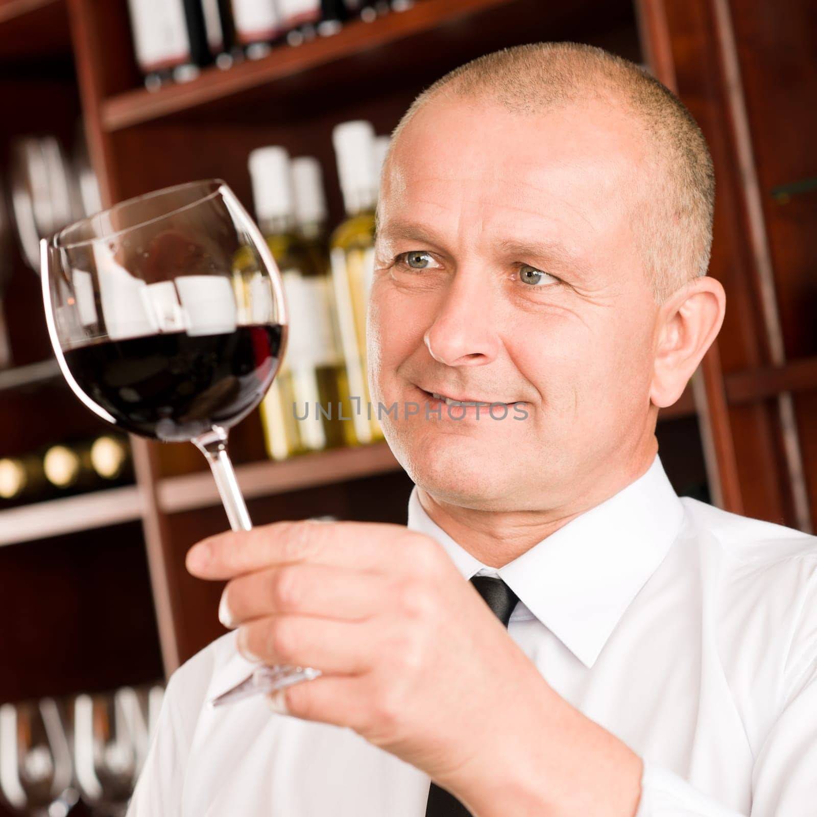 Waiter at bar hold glass of red wine in restaurant