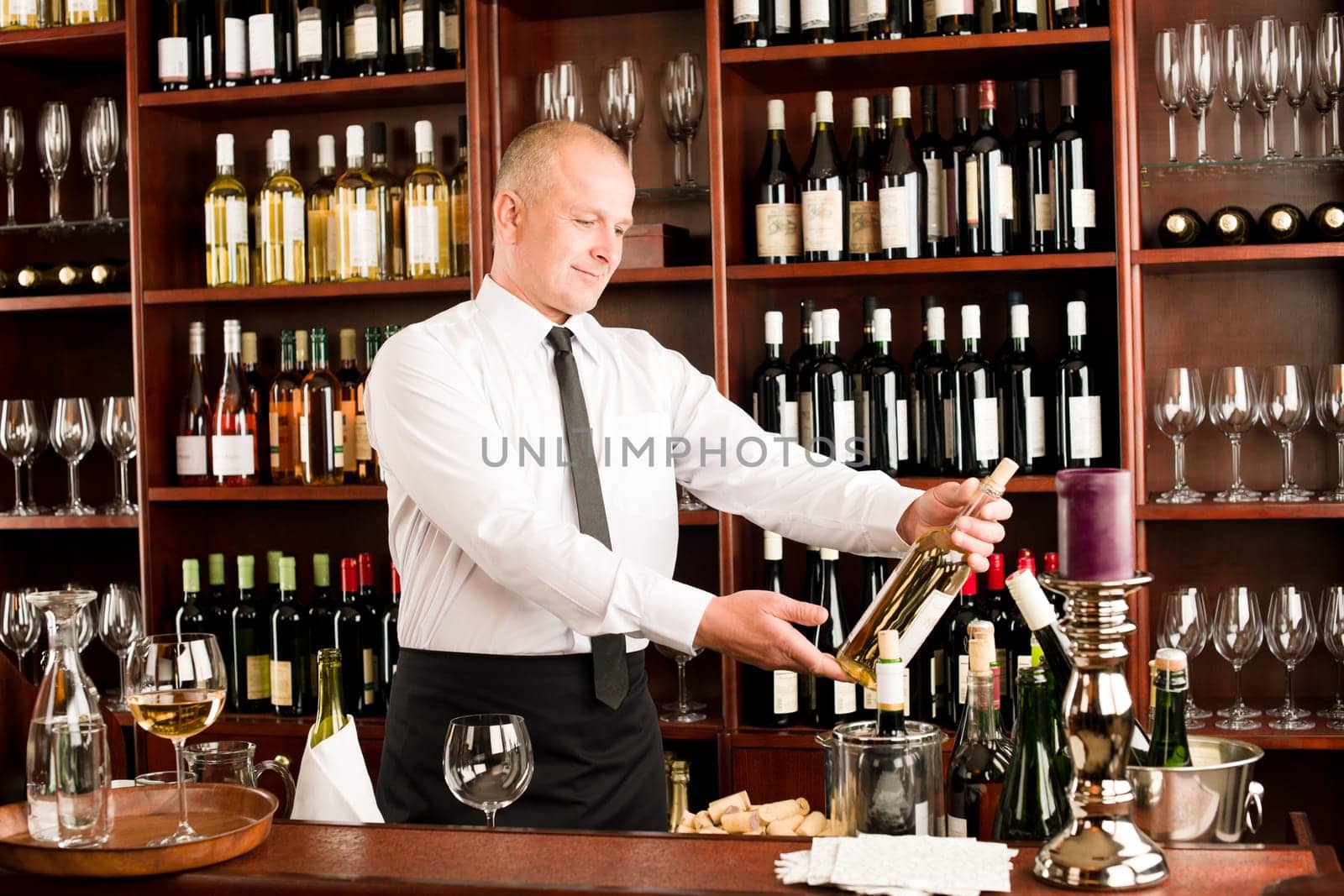 At the bar - waiter hold bottle white wine in restaurant
