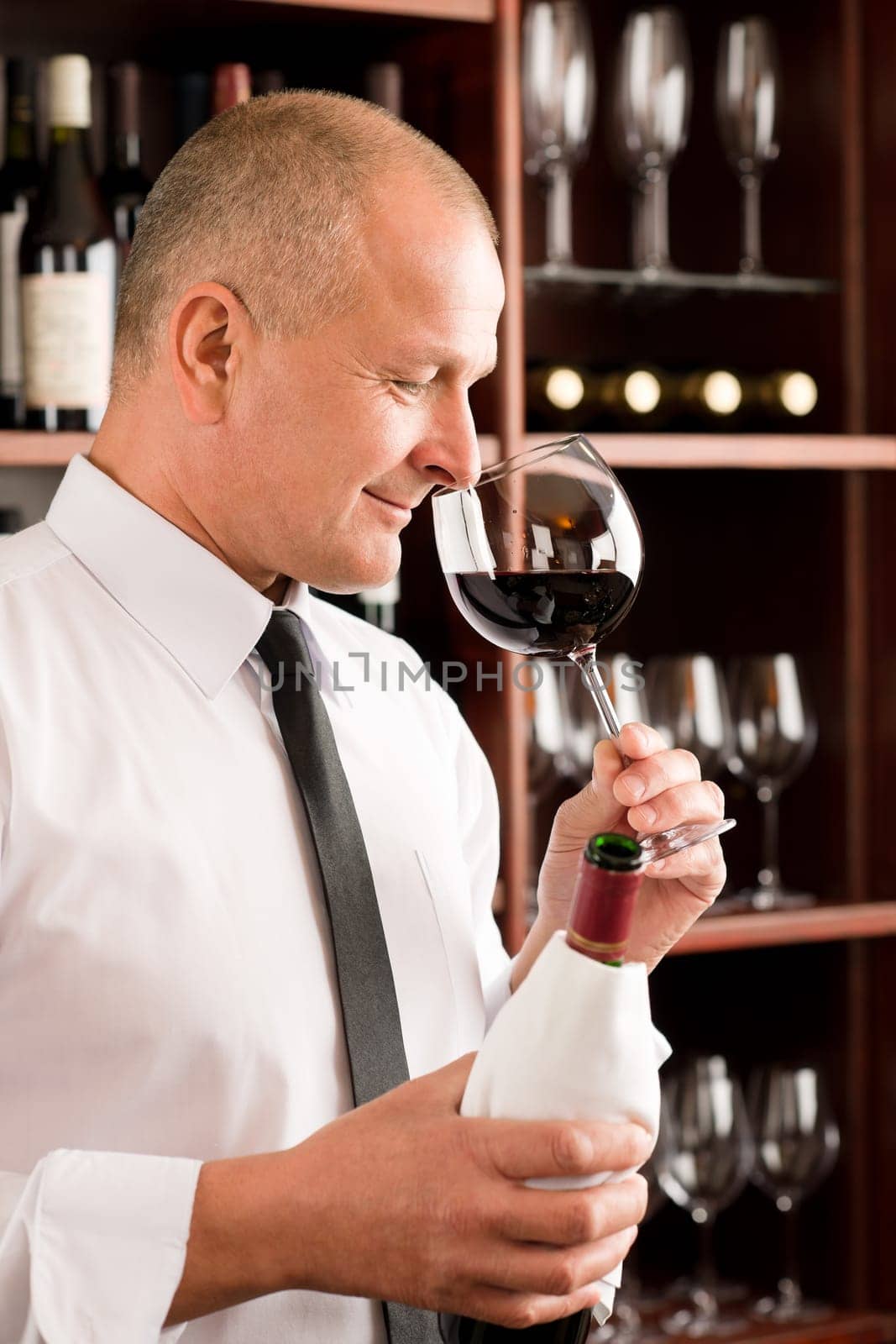 Waiter at bar smell glass of red wine in restaurant