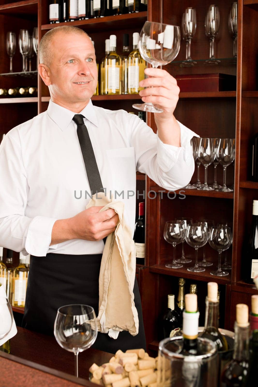 Wine bar waiter looking at clean glass in restaurant