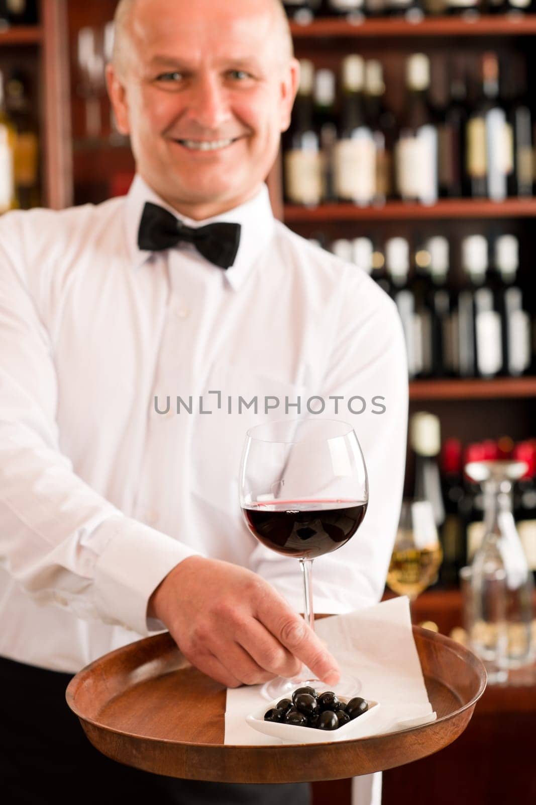 Wine bar waiter mature serving on tray glass olives restaurant