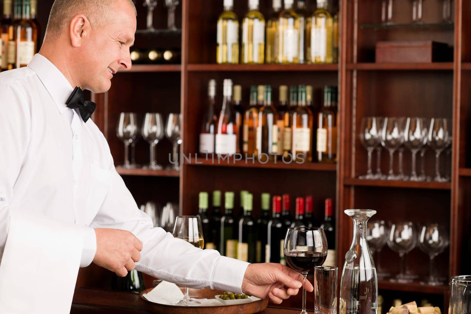 Wine bar waiter mature serving glass in restaurant