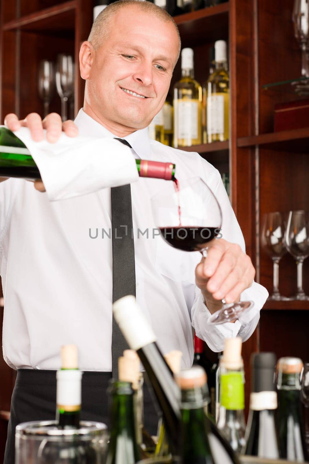 At the bar - waiter pour red wine in glass restaurant