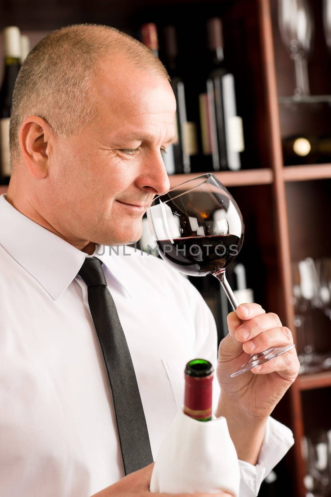 Waiter at bar smell glass of red wine in restaurant